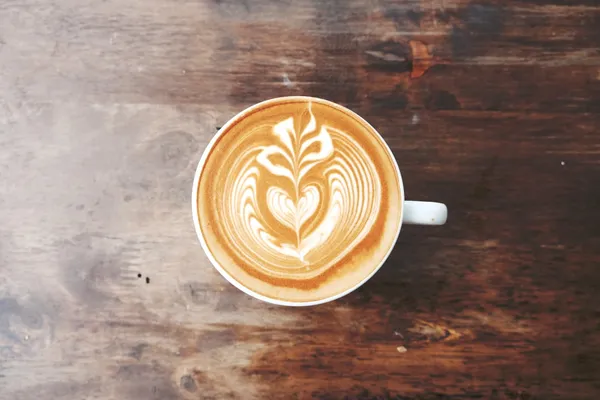 A cappuccino with latte art on a wooden table